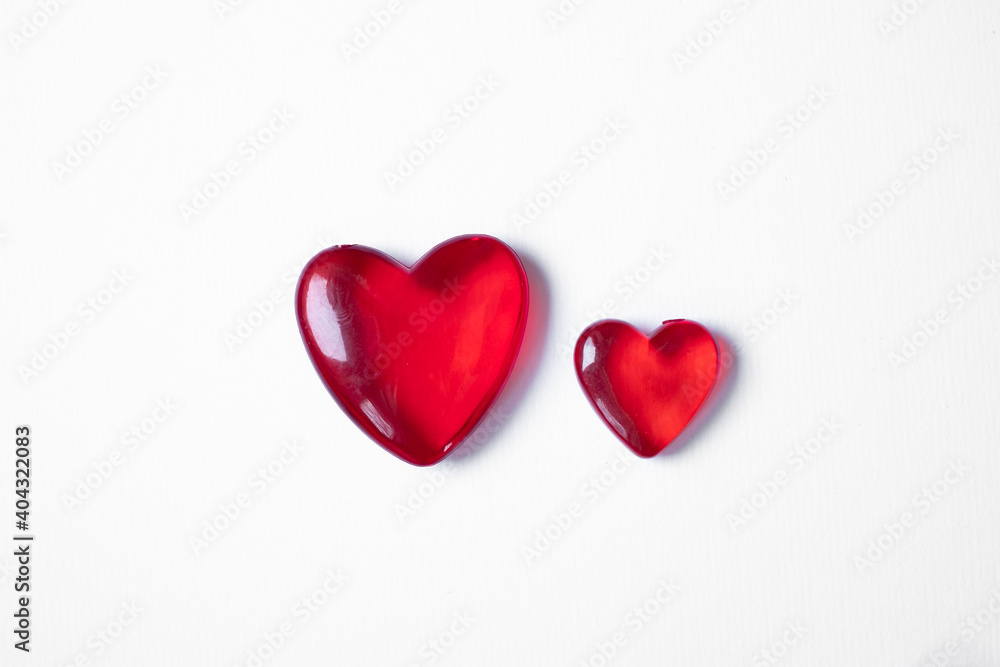 Valentine's day background with two red hearts. Shiny glass hearts on white background.