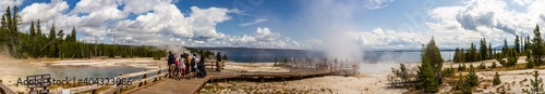 Panorama shot of people going on wooden walkway in thermal lagoons in yellowstone national park in america at sunny day