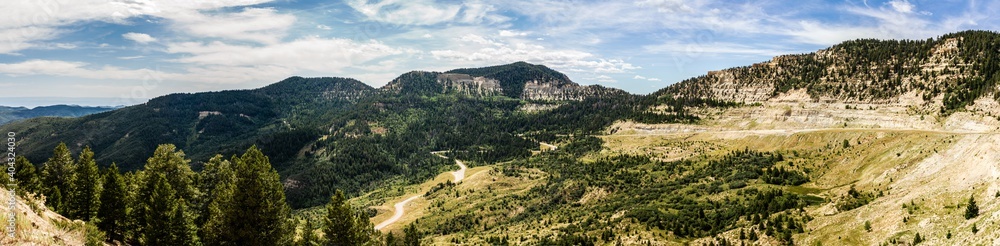 Fototapeta premium Panorama view of road goes in green rocky valley in american country at sunny day
