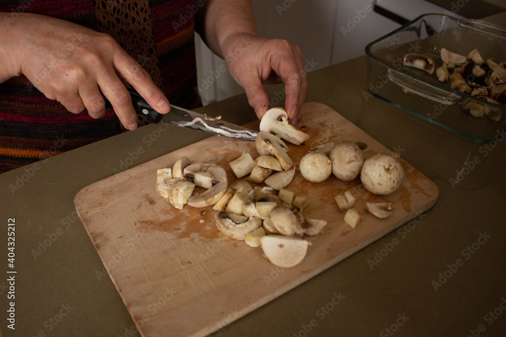 selective focus, woman's hand is cutting the mushrooms on the cutting board, slicing the mushrooms in kitchen.top view.
