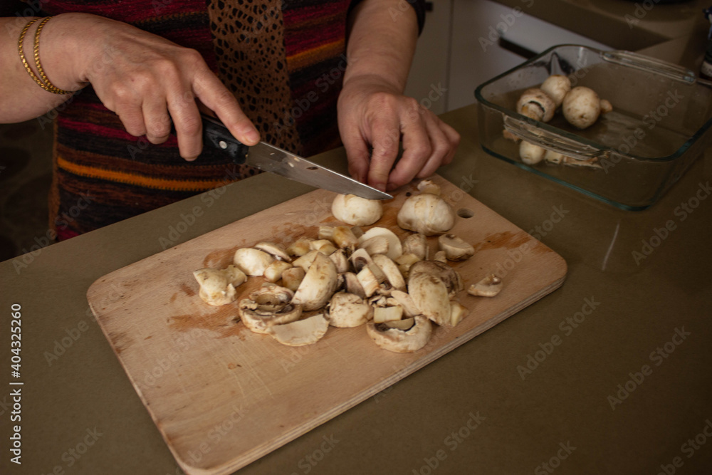 top view, woman's hand is cutting the mushrooms on the cutting board, slicing the mushrooms in kitchen.selective focus.