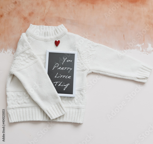 A red heart, a photo frame and a white knitted sweater. Love, romance, Valentines Day. Flat lay, top view, copy space 