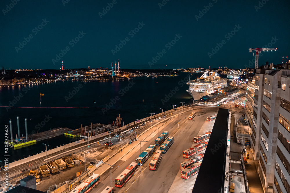 Evening street in Stockholm, cruise ship on the dock, bus depot. Night cityscape from above in warm colors.
