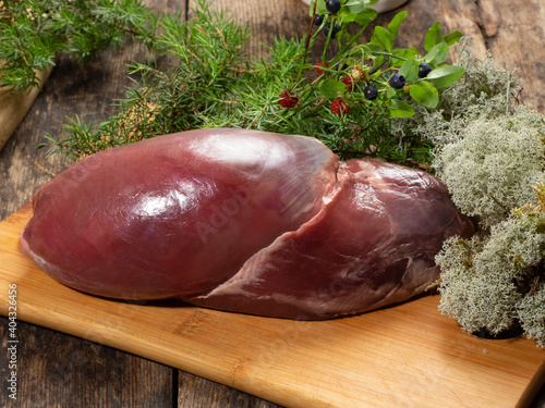 Fresh venison meat on a board with forest plants