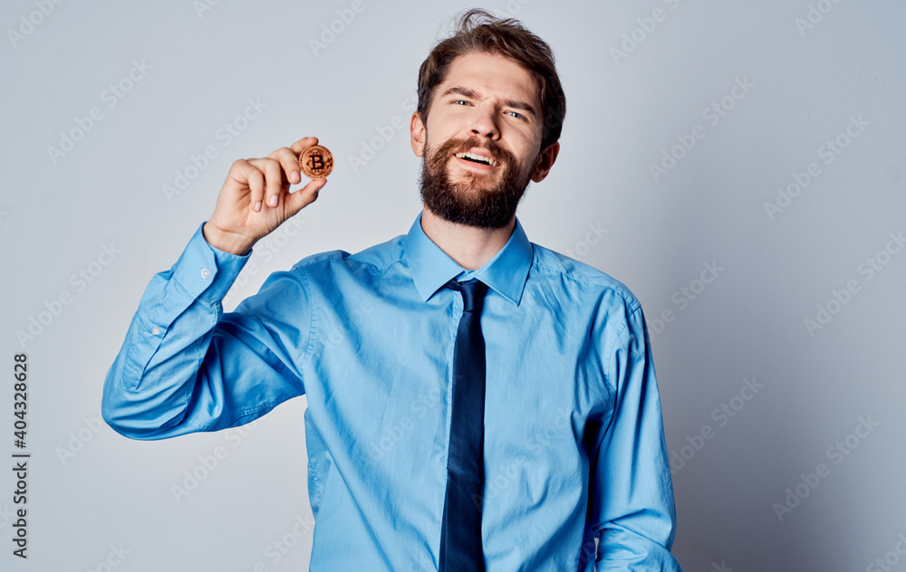 Business man in a blue shirt with a coin in his hand cryptocurrency Bitcoin finance model Business man in a blue shirt with a coin in his hand cryptocurrency Bitcoin finance model