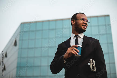 Businessman with takeaway coffee in front of the skyscraper. photo
