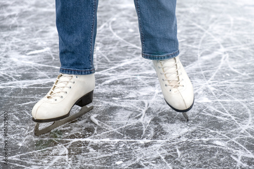 casual woman look in ice skates and jeans on ice macro