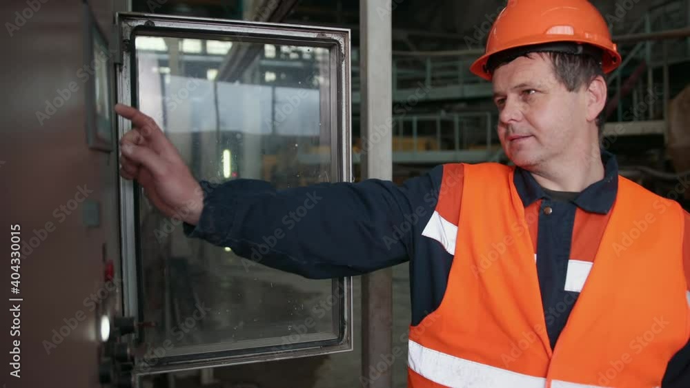 Caucasian worker in overall helmet on head pressing button dashboard. Oil production. Emergency button, while operator is clamping a vise, hand pressing machine control panel at factory Caucasian worker in overall helmet on head pressing button dashboard. Oil production. Emergency button, while operator is clamping a vise, hand pressing machine control panel at factory