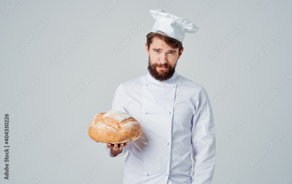 Cropped view of a professional chef with a prepared loaf of bread in hand on a light background Cropped view of a professional chef with a prepared loaf of bread in hand on a light background