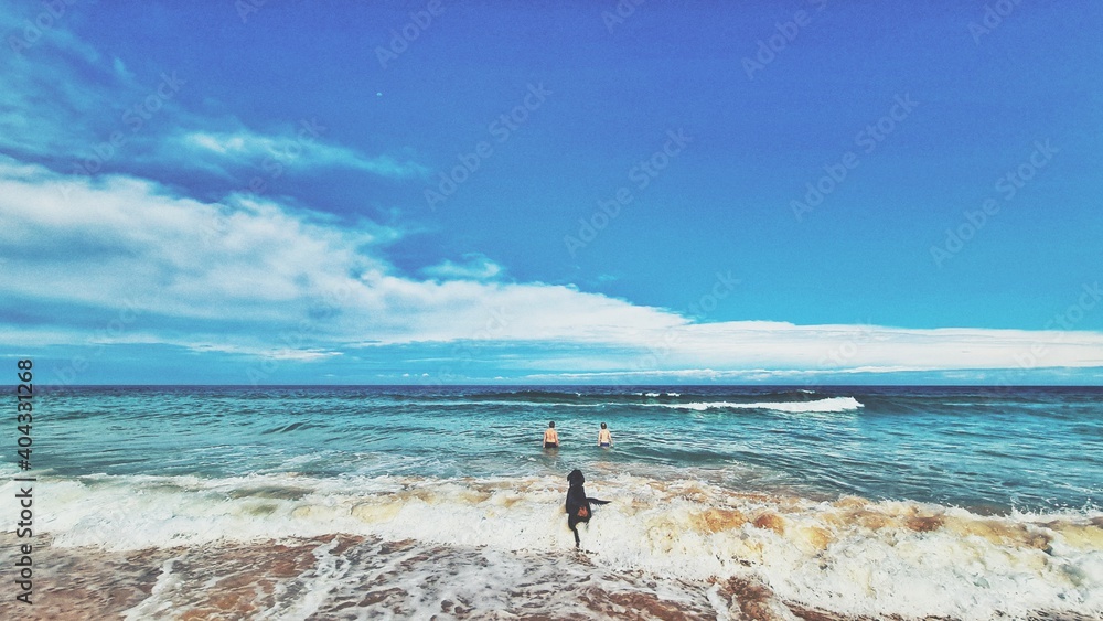 Φωτογραφία Two boys and rottweiler dog swimming in surf at the beach on NSW south coast, Au
