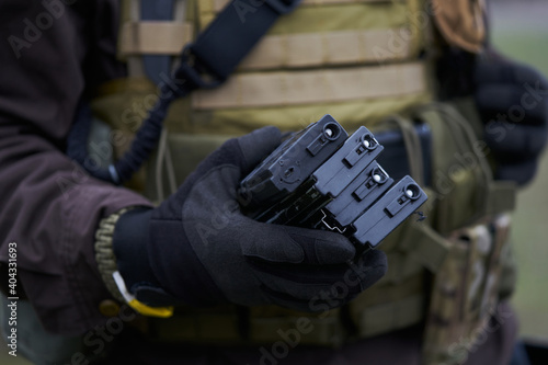 Airsoft player holds magazines for a machine gun in his hand