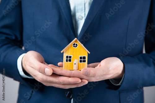 man holding wooden house model