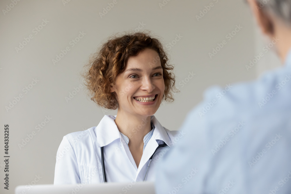 Φωτογραφία Head shot happy young pretty female general practitioner doctor in white coat looking at patient, sharing good illness treatment news or feeling satisfied with health condition at appointment meeting