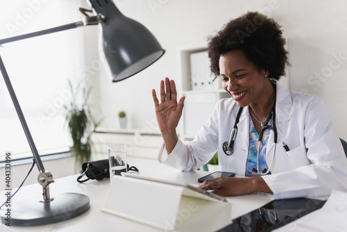 African American woman doctor working at her office doing telemedicine services. Helping patients online and by the phone. Primary care consultations photo