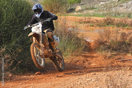 Zoom photo of professional motocross rider on his motorcycle on extreme dirt and mud terrain track. Biker flying on a motocross motorcycle.