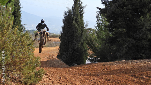 Zoom photo of professional motocross rider on his motorcycle on extreme dirt and mud terrain track. Biker flying on a motocross motorcycle.