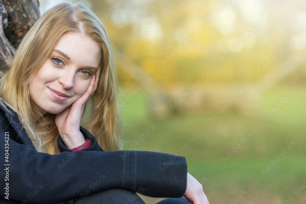 Portrait of young girl in autumn park. The girl is smiling at the camera. Portrait of young girl in autumn park. The girl is smiling at the camera.