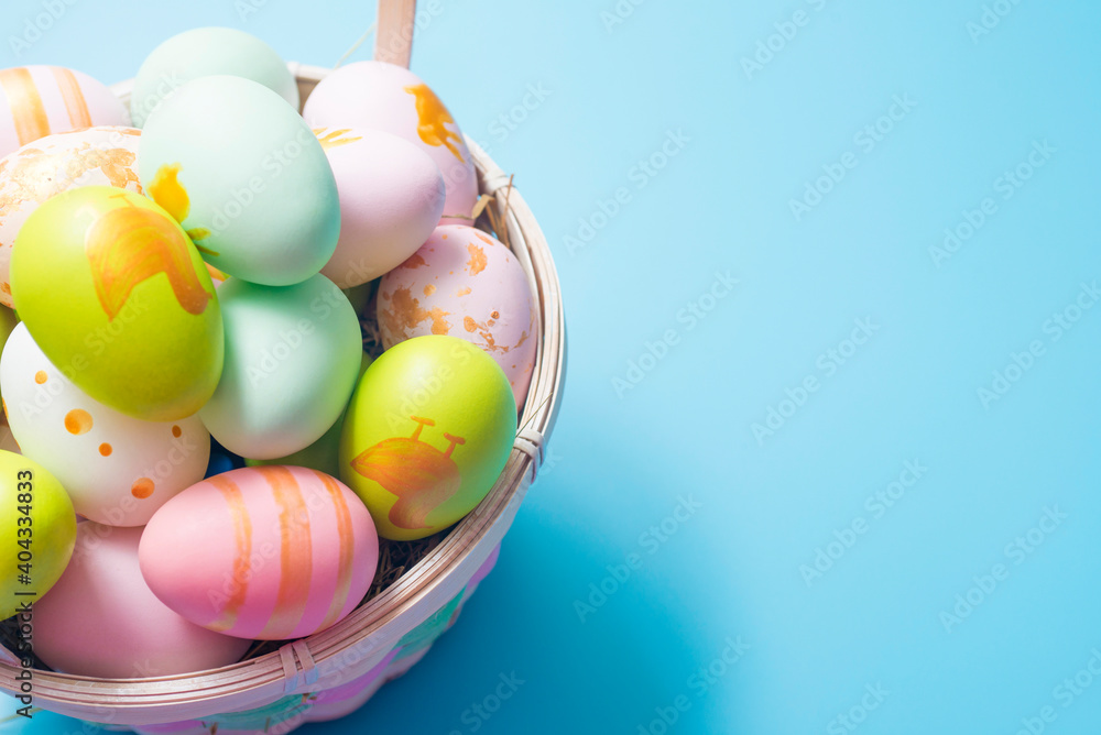 Easter basket filled with painted Easter Eggs over a blue background. Colorful painted easter eggs in basket on blue background Easter basket filled with painted Easter Eggs over a blue background. Colorful painted easter eggs in basket on blue background