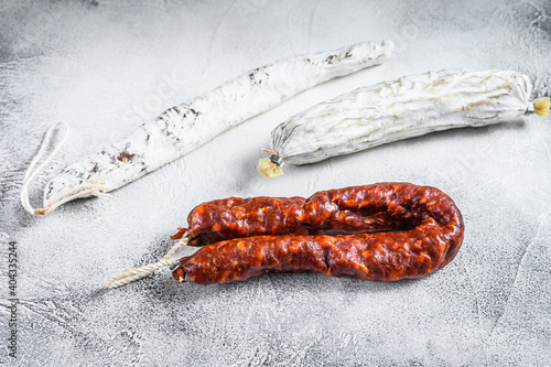 Spanish salami, fuet and chorizo sausages on a kitchen table. White background. Top view