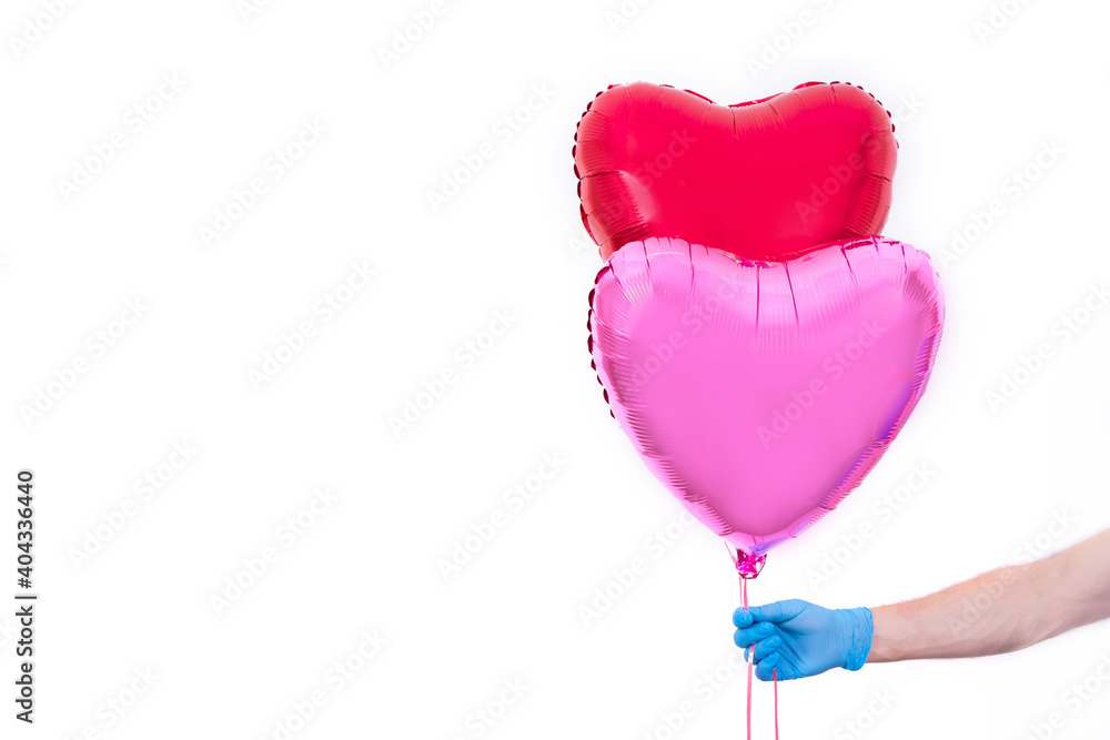 Courier in protective gloves holds red heart-shaped balloon for Valentine's Day. Safe contactless home delivery of gifts to your favorite women on Mother's and Women's Day.I love you. Hand close up.