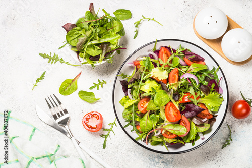 Green salad from fresh salad leaves and vegetables in white plate. Healthy vegan food. Top view image.