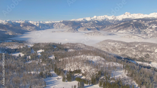 AERIAL: Beautiful aerial view of a fog covered valley and the snowy Julian Alps.