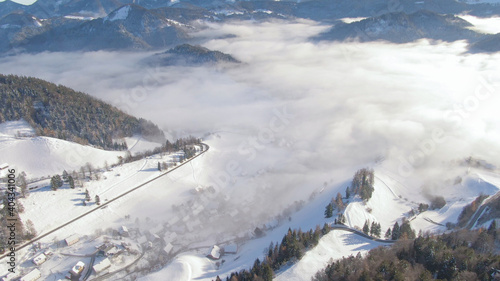 AERIAL: Flying above the idyllic snowy countryside in Bohinj wrapped in fog.