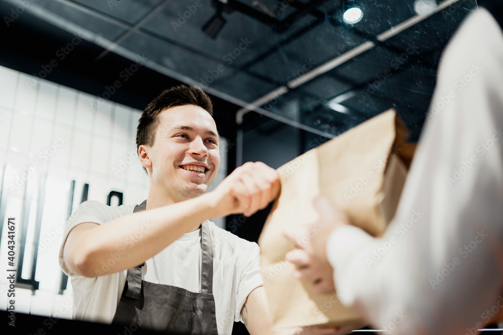 Buys lunch food healthy vegetables pasta in a paper bag with a takeaway. small business pizzeria coffee shop. a young male employee picks up dinner. convenient delivery in a corrugated cardboard box. Buys lunch food healthy vegetables pasta in a paper bag with a takeaway. small business pizzeria coffee shop. a young male employee picks up dinner. convenient delivery in a corrugated cardboard box.
