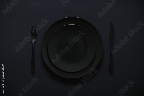 Plates nicely served for a meal. Everything is black. Festive lunch concept.