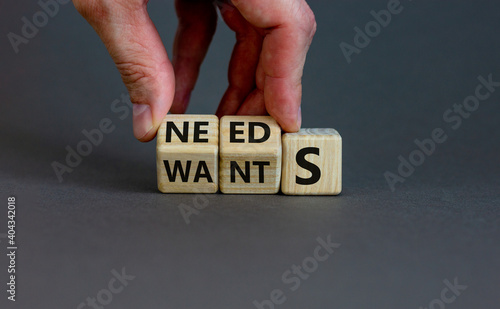 Wants or needs symbol. Hand turns cubes and changes the word 'wants' to 'needs'. Beautiful grey background, copy space. Valentines day and wants or needs concept. photo