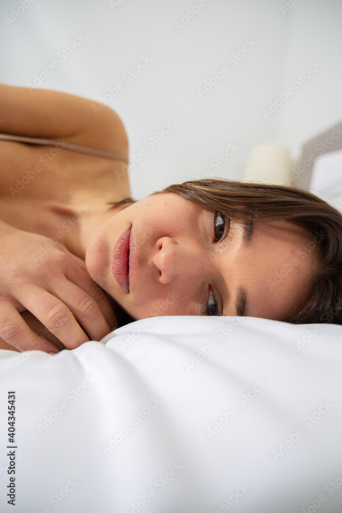 A depressed woman is lying in bed looking ahead with distracted eyes. She is sad and lonely. Mental health problems. A young woman feels pain and isolation while being at home. A depressed woman is lying in bed looking ahead with distracted eyes. She is sad and lonely. Mental health problems. A young woman feels pain and isolation while being at home.
