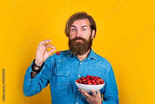 Who cares about diet. cherries for breakfast. cheerful male hipster hold fresh berry. fruit full of vitamin. only organic food. dieting and healthy lifestyle. happy bearded man with sweet cherry