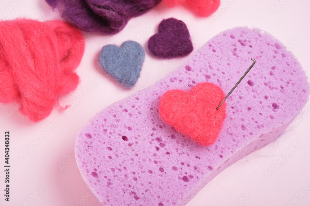hearts made of wool, needles for felting, a sponge and skeins of wool, the process of felting from wool hearts made of wool, needles for felting, a sponge and skeins of wool, the process of felting from wool