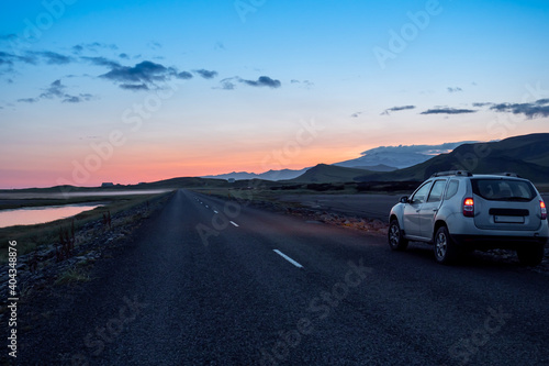 Gravel road with car and dramatic sunset in southern fjords, Iceland