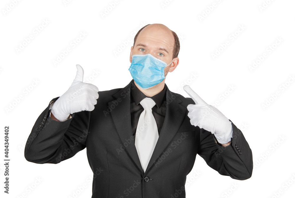 Handsome young business man holding surgical medical virus protection mask with white gloves showing thumbs up isolated Handsome young business man holding surgical medical virus protection mask with white gloves showing thumbs up isolated