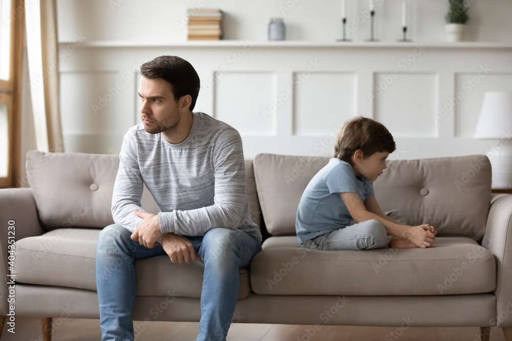 Φωτογραφία Unhappy young Caucasian man father and little 6s son sit separate ignore each other after family fight