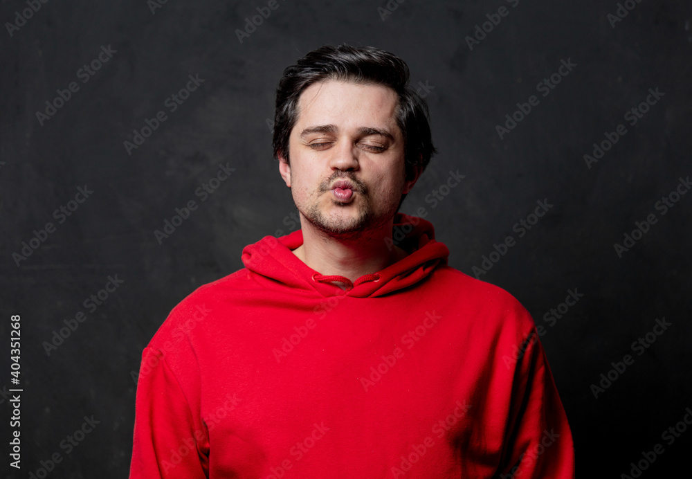 White guy in red sweatshirt give a kiss on dark background