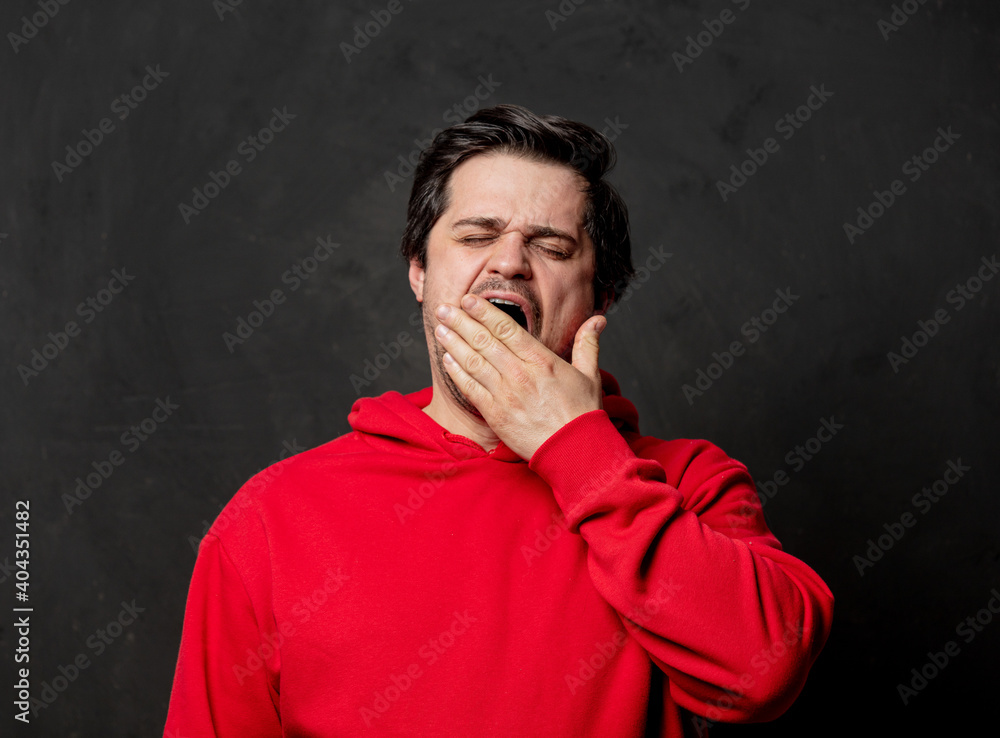 White guy in red sweatshirt yawn on dark background White guy in red sweatshirt yawn on dark background