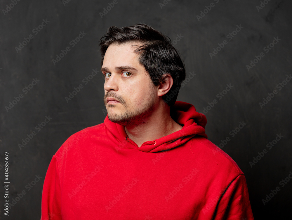 White surprised guy in red sweatshirt on dark background
