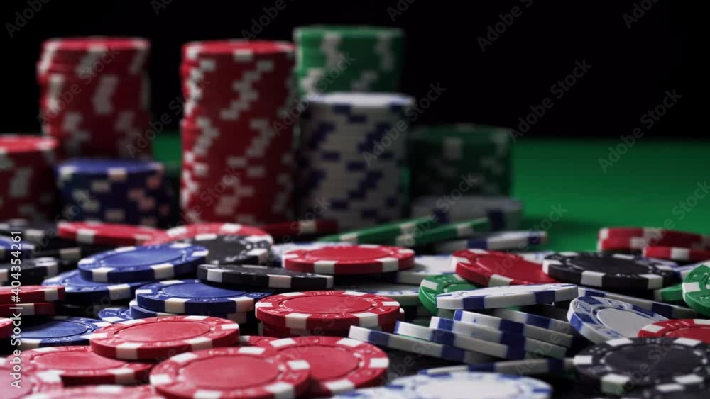 Poker chips at stake are on a green table in close-up. Equipment for playing at hazard games in a casino on black background. Winning and losing money theme. Gambling as entertainment at leisure time. Poker chips at stake are on a green table in close-up. Equipment for playing at hazard games in a casino on black background. Winning and losing money theme. Gambling as entertainment at leisure time.