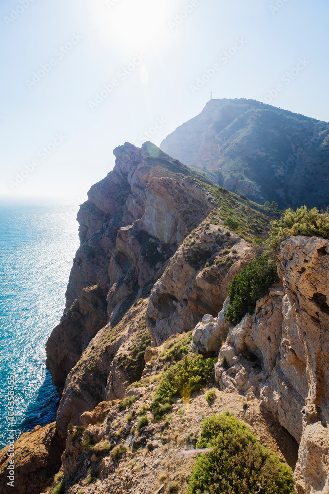 Mediterranean landscape with steep rocky cliffs falling into bright ocean at natural park 'Serra Gelada' in Albir, Spain