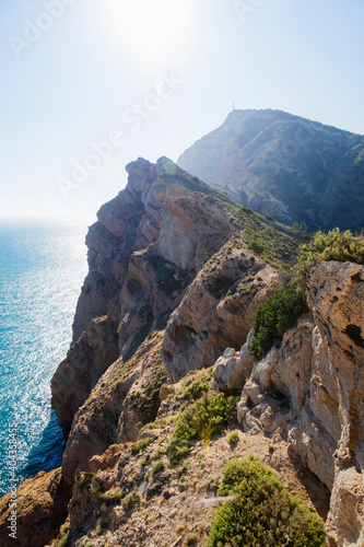 Mediterranean landscape with steep rocky cliffs falling into bright ocean at natural park 'Serra Gelada' in Albir, Spain