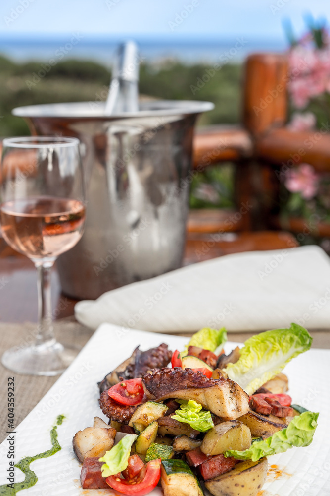 Octopus salad with glass of rose wine, wine cooler and sea view