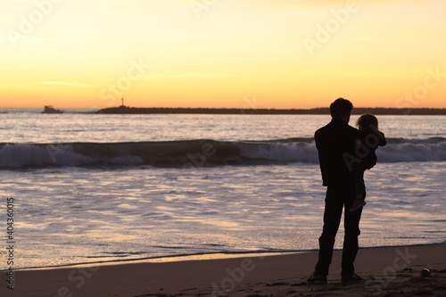 silhouette of man and child at beach during sunset