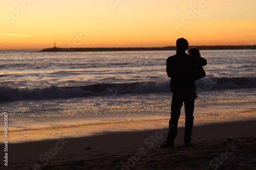silhouette of man and child at beach during sunset