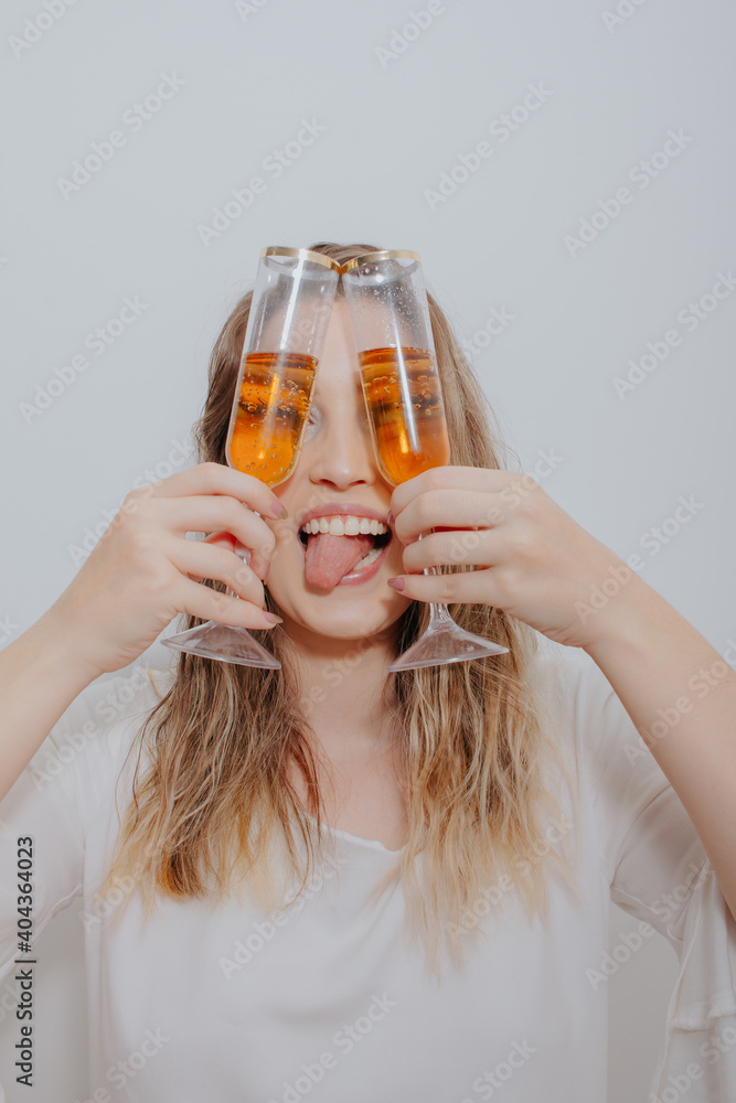 young woman in white dress and with two glasses of sparkling wine in hands in front of her face. young woman in white dress and with two glasses of sparkling wine in hands in front of her face.