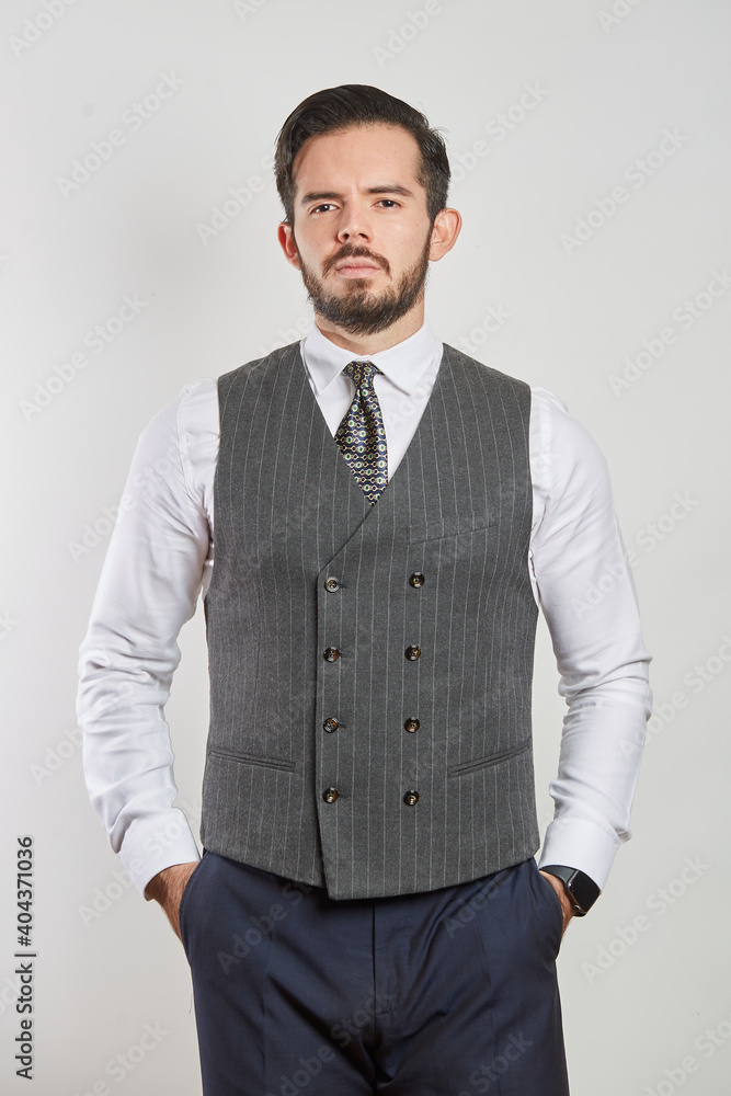 Fototapeta premium A young Latino businessman standing in a vest and tie on a white background