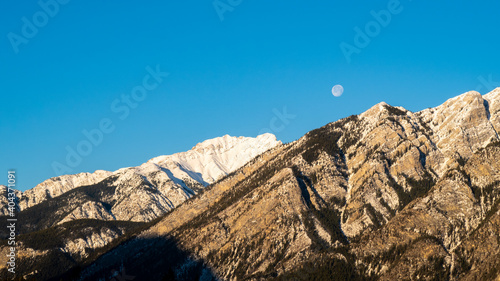 Full moon setting behind mountains in Banff national park, Canada