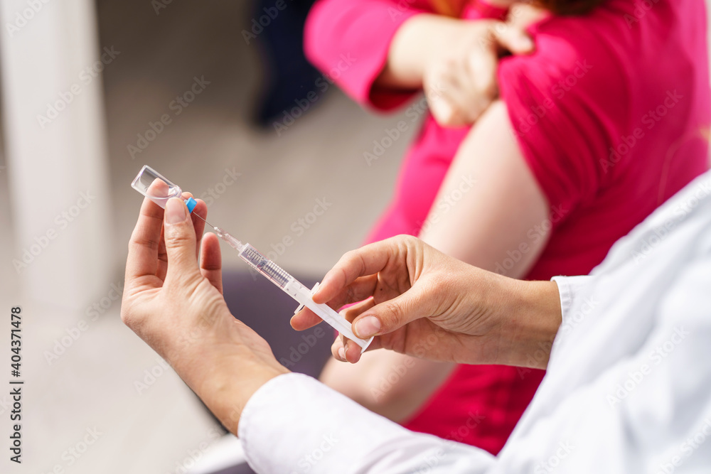 Vaccination healthcare concept - Hands of doctor or nurse hold a syringe and ampule preparing a shot of corona virus covid-19 hpv or flu vaccine for unknown patient - copy space close up Vaccination healthcare concept - Hands of doctor or nurse hold a syringe and ampule preparing a shot of corona virus covid-19 hpv or flu vaccine for unknown patient - copy space close up