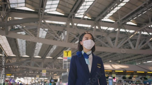 Caucasian flight attendant wearing face mask, walking in the airport. photo